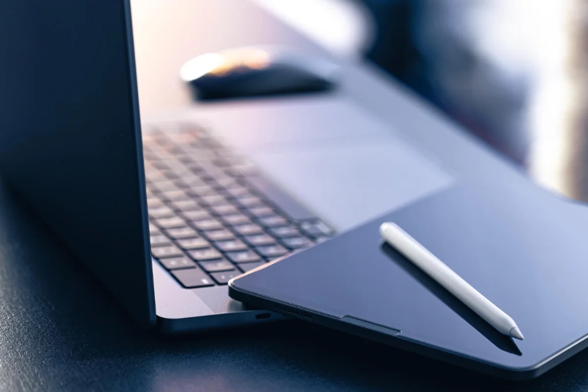 A laptop and tablet with a stylus on a desk