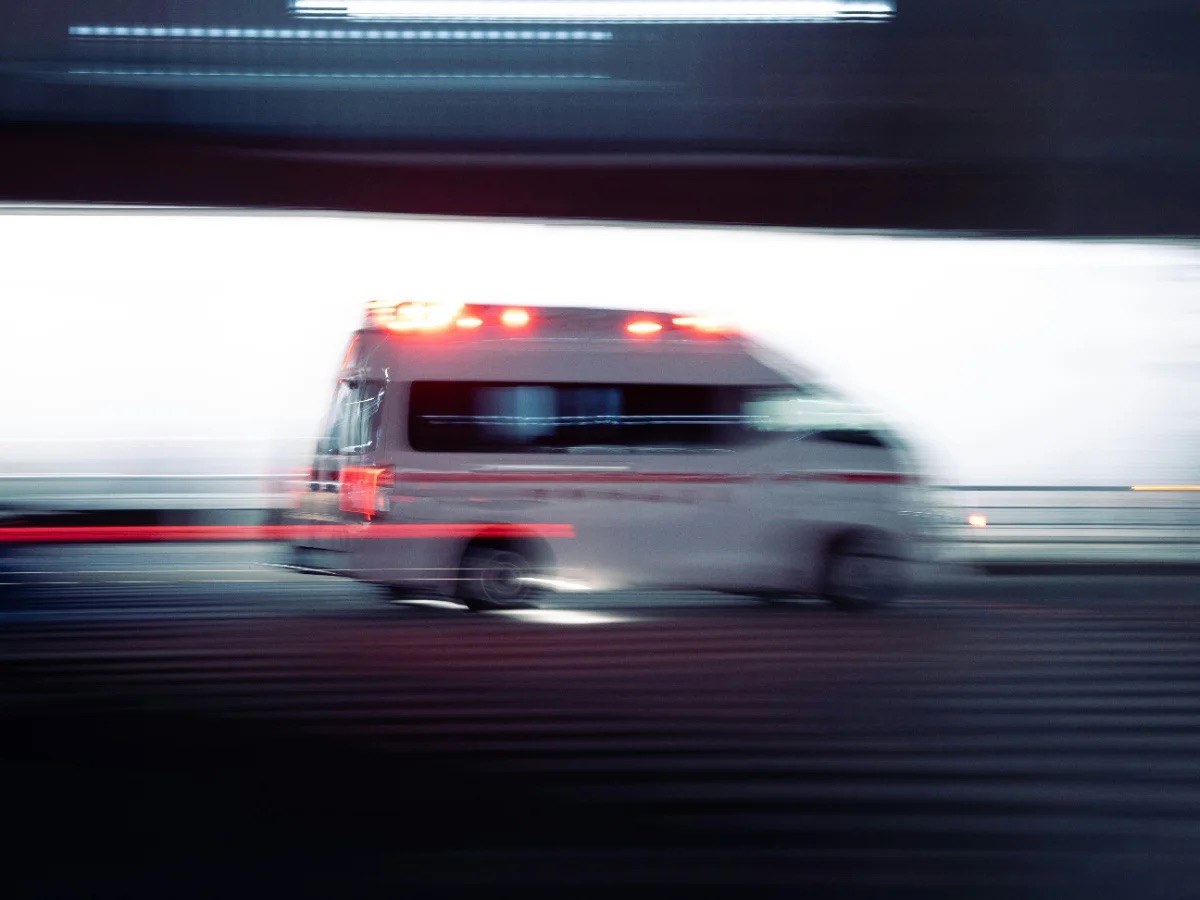 An ambulance with its lights on, moving at speed